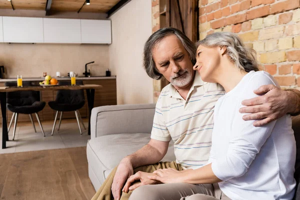 Happy middle aged couple sitting on sofa in living room — Stock Photo