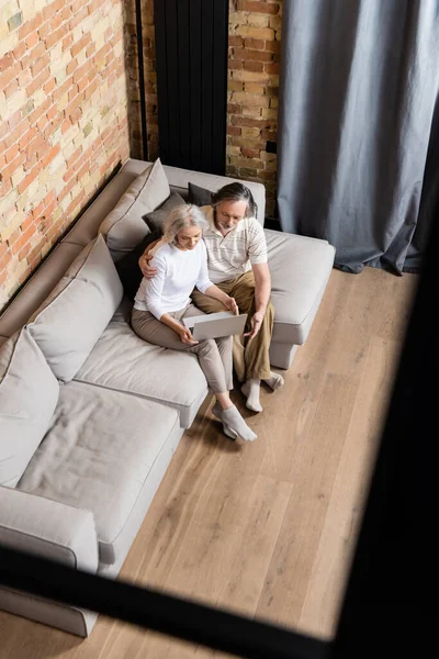 Vista aérea de la pareja adulta utilizando el ordenador portátil en casa - foto de stock