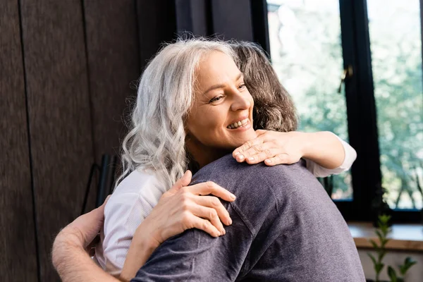 Allegra donna di mezza età che abbraccia con il marito a casa — Foto stock