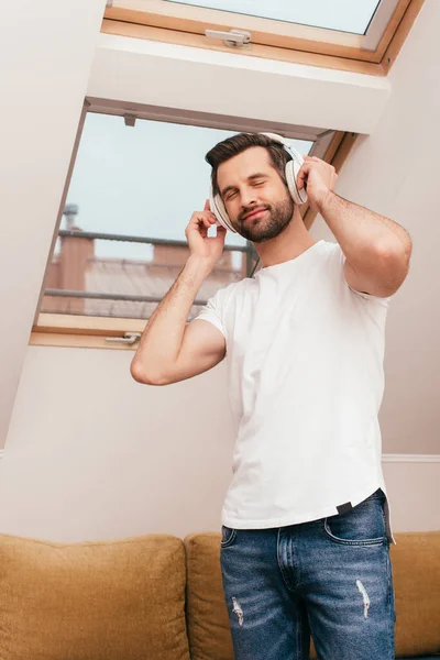 Hombre guapo escuchando música en auriculares en casa - foto de stock