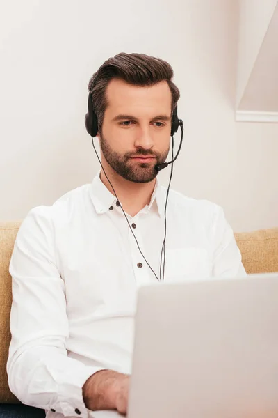 Focus selettivo del bel telelavoro che utilizza laptop e auricolari a casa — Foto stock