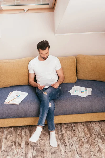 Schöner Mann arbeitet mit Papieren auf Couch zu Hause — Stockfoto