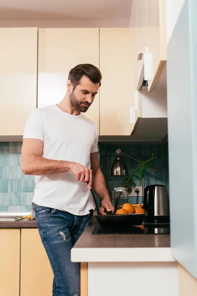 Selektiver Fokus eines gutaussehenden Mannes, der Frühstück in der Küche kocht — Stockfoto