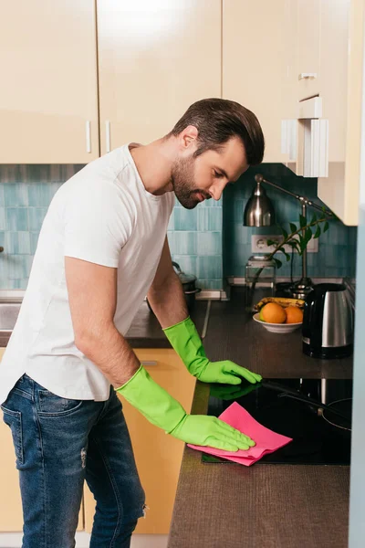 Seitenansicht eines gutaussehenden Mannes, der den Herd in der Küche reinigt — Stock Photo