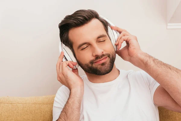 Schöner Mann mit geschlossenen Augen, der zu Hause über Kopfhörer Musik hört — Stockfoto
