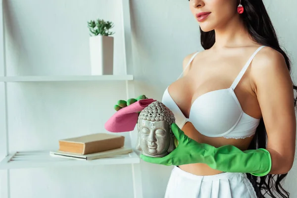 Vista ritagliata di ragazza sexy in reggiseno e guanti di gomma pulizia statuetta decorativa a casa — Foto stock