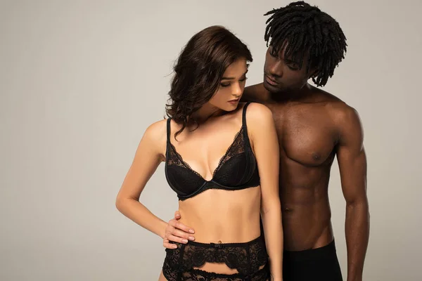 Schöne sexy multiethnische Paar umarmt isoliert auf grau — Stockfoto