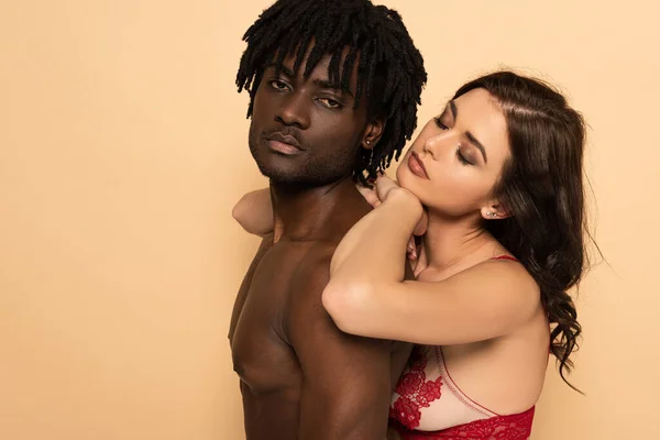 Sexy namorada abraçando sem camisa afro-americano namorado isolado no bege — Fotografia de Stock