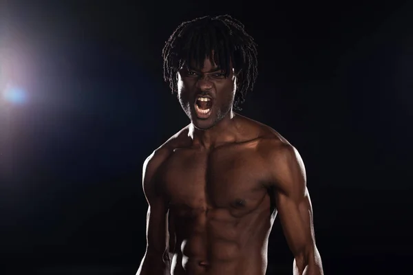 Sexy aggressive african american man yelling on black with back light — Stock Photo