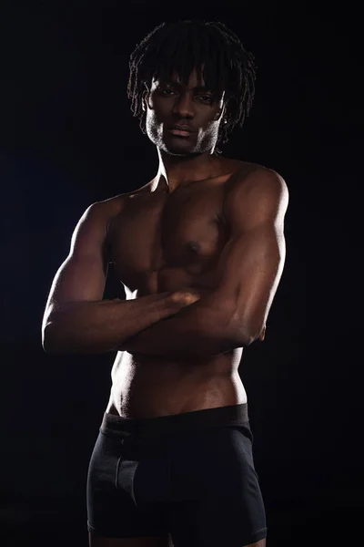 Hombre americano africano musculoso sin camisa con brazos cruzados aislados en negro - foto de stock