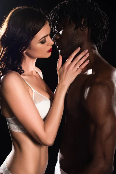 Sexy interracial casal no cueca abraçando e indo para beijo isolado no preto — Fotografia de Stock