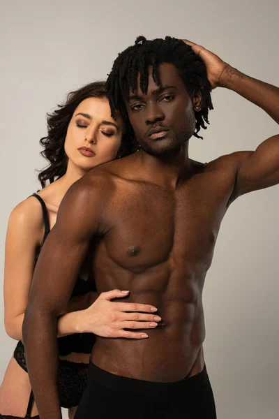 Schöne sexy interracial Paar umarmt zusammen isoliert auf grau — Stockfoto