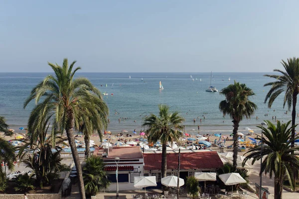 Каталония, Испания - 30 апреля 2020 года: люди отдыхают на пляже с яхтами в море и голубым небом на заднем плане — стоковое фото