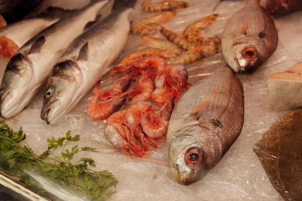 Vista de cerca de los mariscos crudos cerca de los verdes en el hielo en el mostrador de la tienda - foto de stock