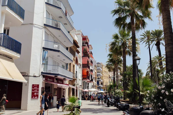 CATALONIE, ESPAGNE - 30 AVRIL 2020 : Des gens marchent dans la rue urbaine avec des palmiers et un café en plein air — Photo de stock