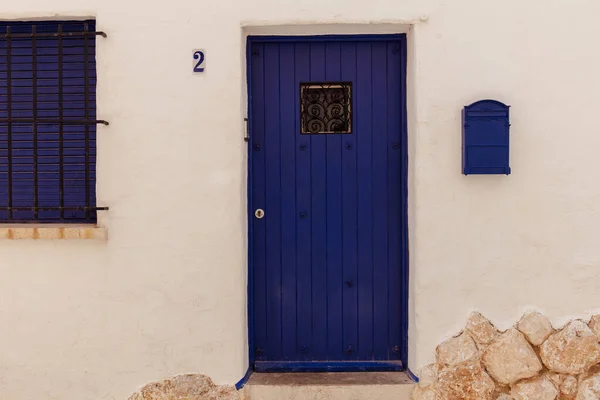 Blue mailbox and wooden door near number of house in Catalonia, Spain — Stock Photo