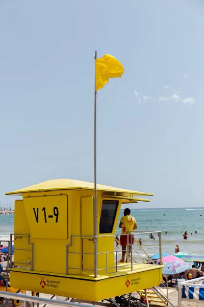 CATALONIA, SPAIN - APRIL 30, 2020: Rescuer standing in lifeguard tower with flag on beach — Stock Photo