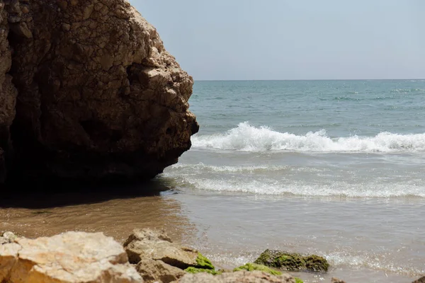 Focus selettivo di pietre con alghe sulla costa del mare con cielo blu sullo sfondo in Catalogna, Spagna — Foto stock