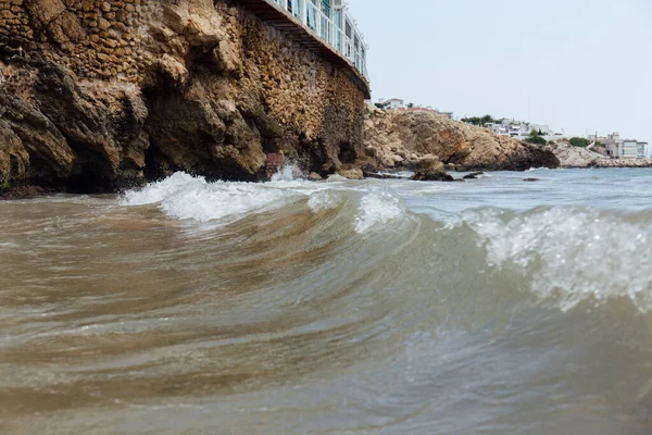 Focus selettivo di costruire sulla costa del mare con onde e cielo blu sullo sfondo in Catalogna, Spagna — Foto stock