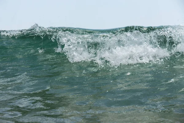 Vue rapprochée de la vague de mer avec mousse et ciel bleu en arrière-plan — Photo de stock