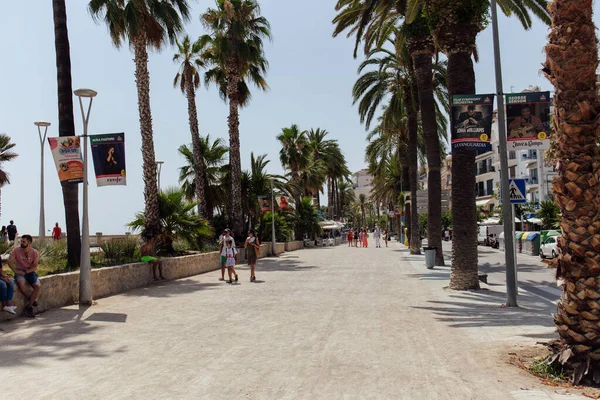CATALÔNIA, ESPANHA - 30 DE ABRIL DE 2020: Pessoas andando na rua urbana perto de palmeiras — Fotografia de Stock