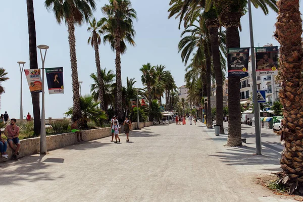 KATALONIEN, SPANIEN - 30. April 2020: Menschen gehen in der Nähe von Palmen auf städtischen Straßen — Stockfoto