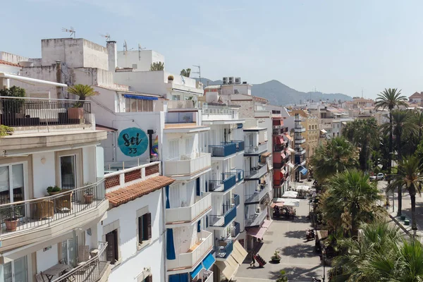 CATALONIE, ESPAGNE - 30 AVRIL 2020 : Rue urbaine avec bâtiments, palmiers et montagnes avec ciel bleu en arrière-plan — Photo de stock