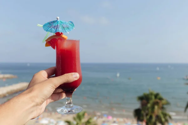 Ausgeschnittene Ansicht eines Mannes mit einem Glas Cocktail mit Meerblick und blauem Himmel im Hintergrund — Stockfoto