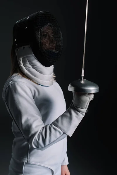 Side view of fencer in fencing mask holing rapier isolated on black — Stock Photo