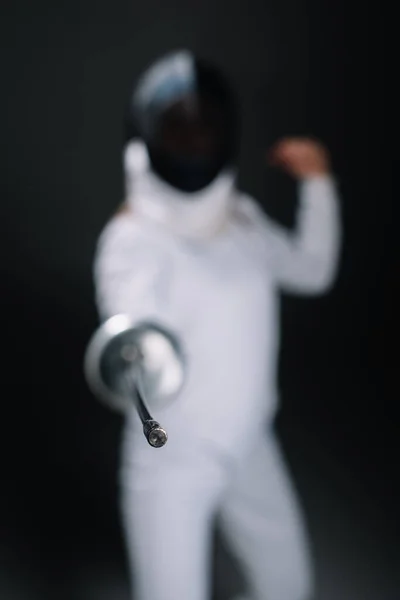 Selective focus of fencer holding rapier isolated on black — Stock Photo