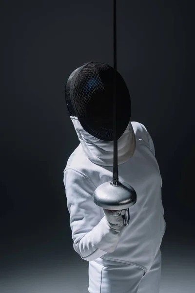 Fencer in fencing mask holding rapier on black background — Stock Photo