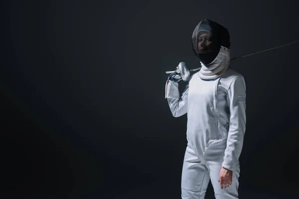 Scherma guardando la fotocamera mentre tenendo rapier isolato su nero — Foto stock