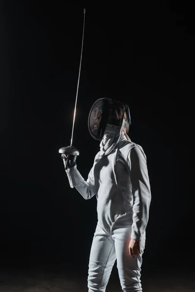 Fencer in fencing mask holding rapier isolated on black — Stock Photo