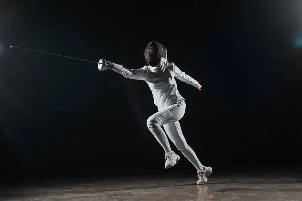 Fencer holding rapier while training on black background — Stock Photo