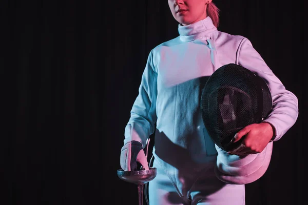 Cropped view of fencer holding rapier and fencing mask isolated on black — Stock Photo