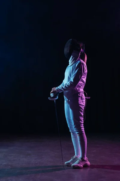 Side view of fencer holding rapier on black background with lighting — Stock Photo