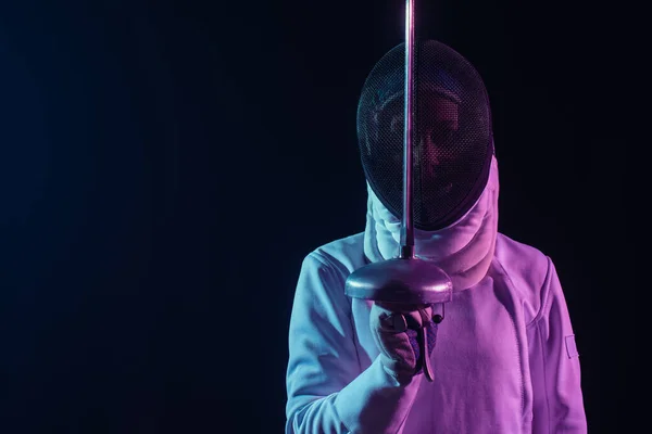 Fencer in fencing mask and glove holding rapier isolated on black — Stock Photo