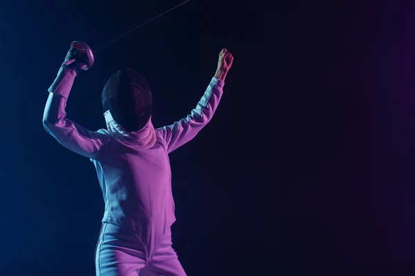 Fencer in fencing mask holding rapier while showing yes gesture isolated on black — Stock Photo