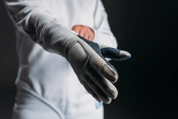 Vista recortada del esgrimista que se pone el guante aislado en negro - foto de stock