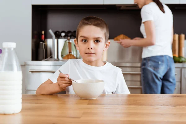 Selektiver Fokus des Jungen, der in die Kamera schaut, während er in der Küche frühstückt — Stockfoto