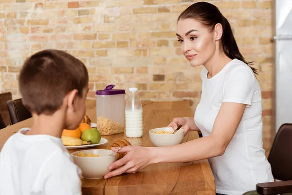 Селективное внимание матери, смотрящей на сына рядом с завтраком на кухонном столе — стоковое фото