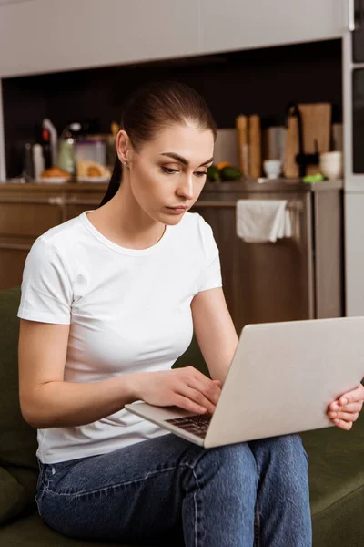 Belle femme utilisant un ordinateur portable sur le canapé à la maison — Photo de stock