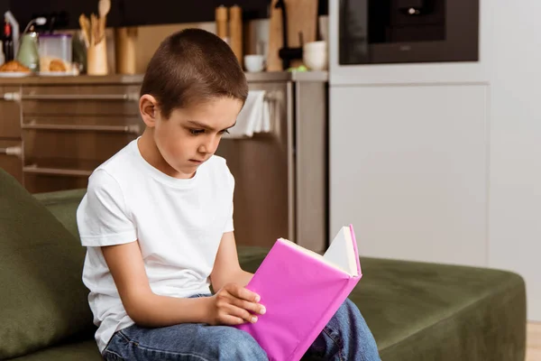 Criança leitura livro no sofá na sala de estar — Fotografia de Stock