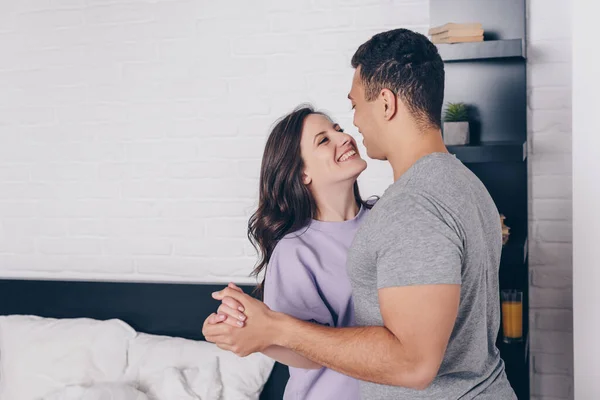 Feliz casal interracial dançando e olhando um para o outro no quarto — Fotografia de Stock