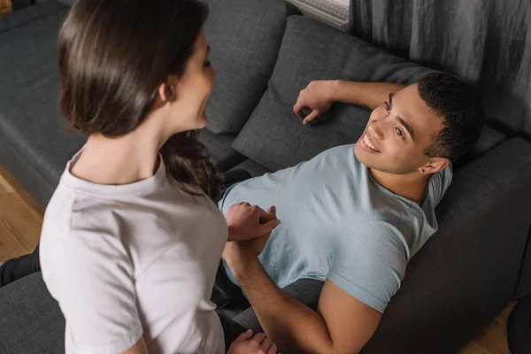 Selective focus of mixed race man looking at girlfriend while holding hands — Stock Photo