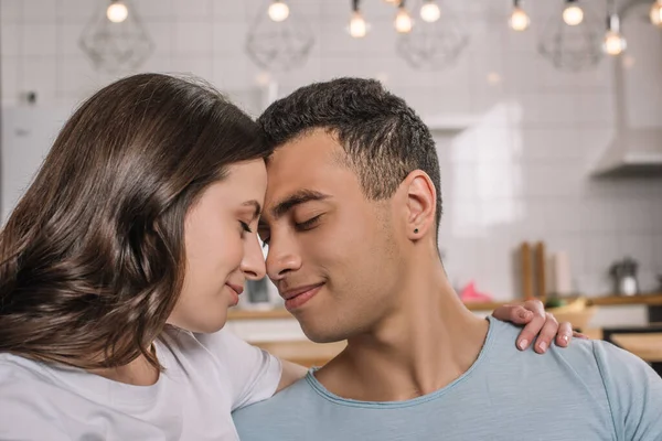 Feliz pareja interracial con los ojos cerrados en casa - foto de stock