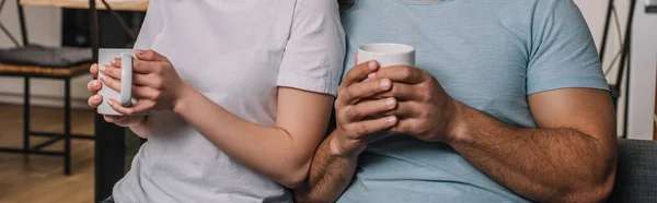 Cultura horizontal de casal interracial segurando copos de café — Fotografia de Stock