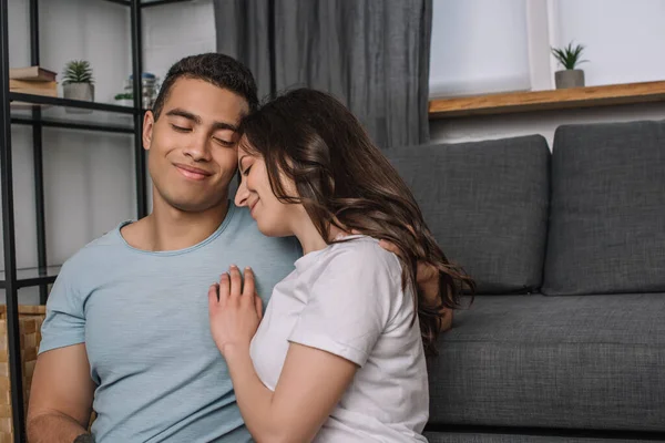 Cheerful woman hugging happy mixed race boyfriend at home — Stock Photo