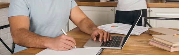Панорамний урожай змішаної раси чоловік пише в ноутбуці поруч з ноутбуком і дівчиною, концепція онлайн-навчання — стокове фото