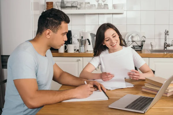 Beau mixte homme de race regardant gai fille tenant des papiers — Photo de stock